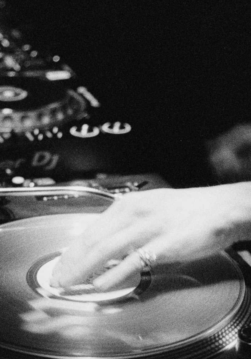 A DJ cueing a vinyl record on the turntable